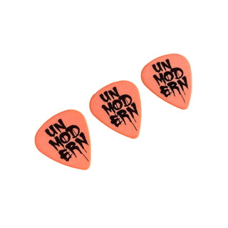 Three orange guitar picks with the word 'UNMODERN' printed in black on each pick.